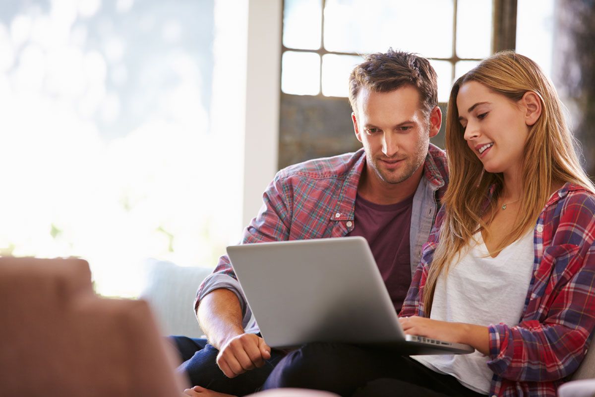 Ein Mann und eine Frau schauen gemeinsam auf einen Laptop
