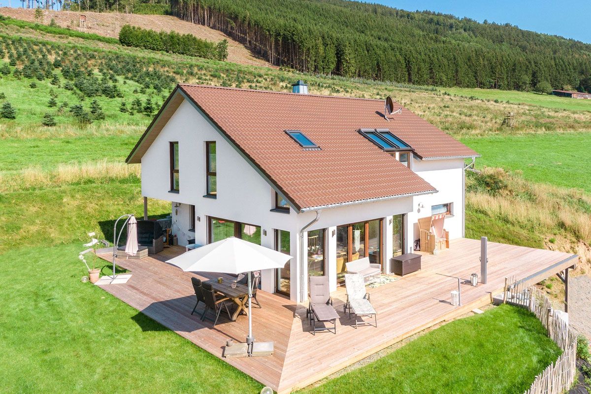 Modernes Fertighaus am Hang mit Satteldach, großer Holzterrasse und Garten