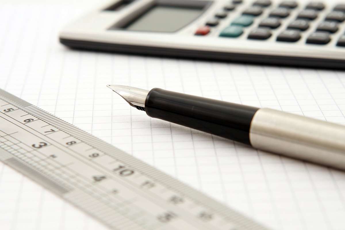 Taschenrechner, Stift und Lineal auf kariertem Papier