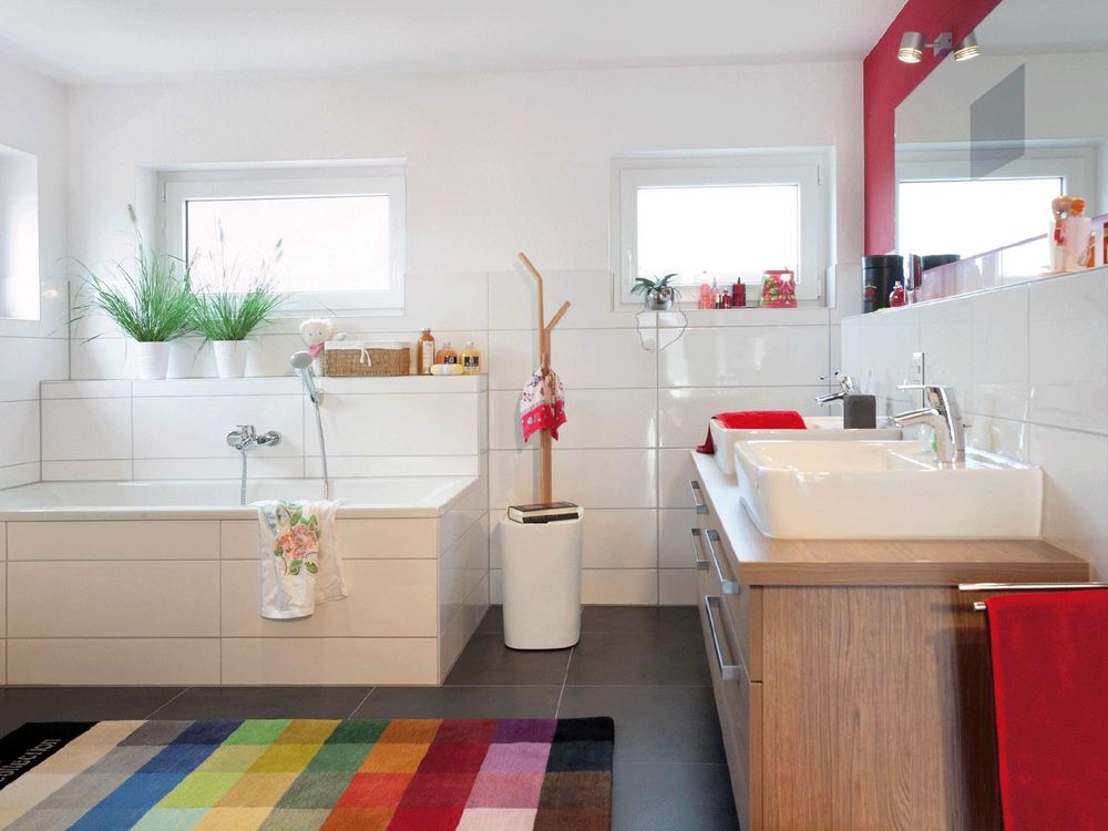 Gefliestes Kinderbadezimmer mit Badewanne und buntem Teppich