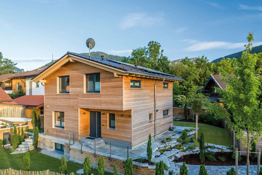 Modernes Fertighaus in Hanglage mit Holzfassade und Garten