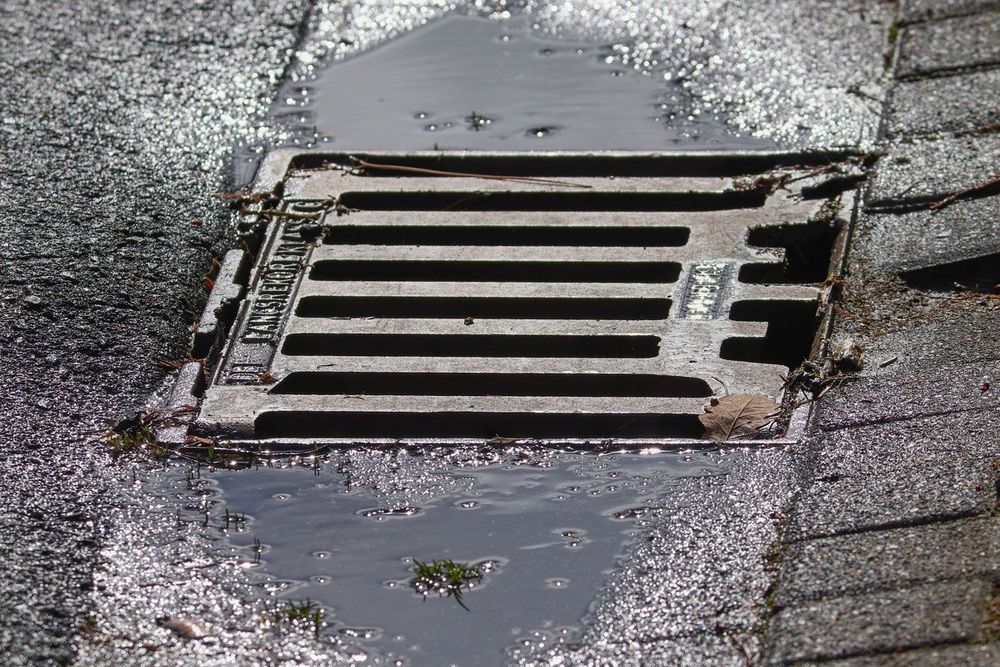 Gully in einer Straße mit Abwasser