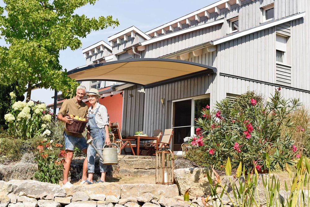 Geschwungene Terrassenüberdachung am Holzhaus mit Garten