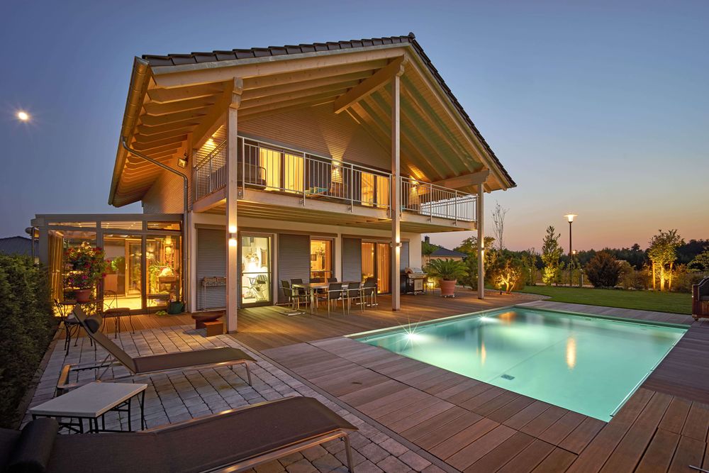 Quadratischer Pool mit Außenbeleuchtung vor einem Holzhaus