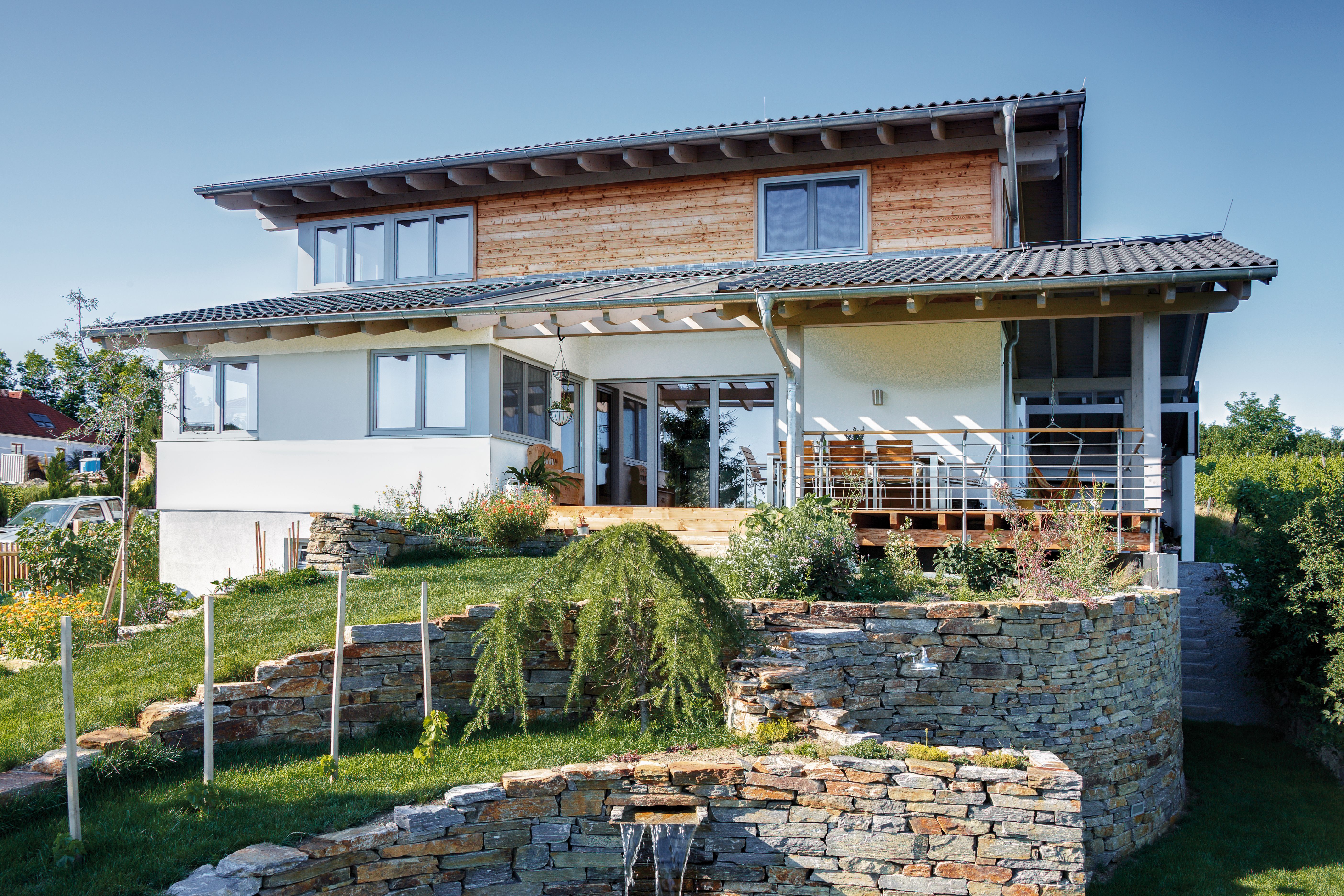 Modernes Holzhaus im Landhausstil auf einem Hanggrundstück