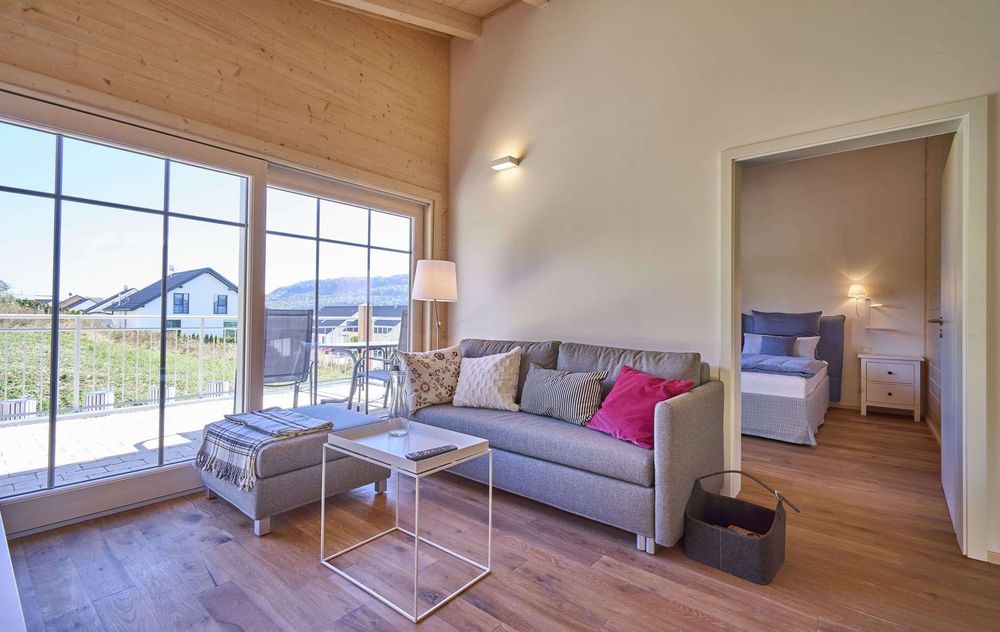 Wohnzimmer mit Glasfront, Holzparkett und Holzverkleidung an den Wänden