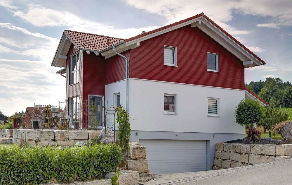 Modernes Fertighaus am Hang mit Satteldach und Putz- und Holzfassade