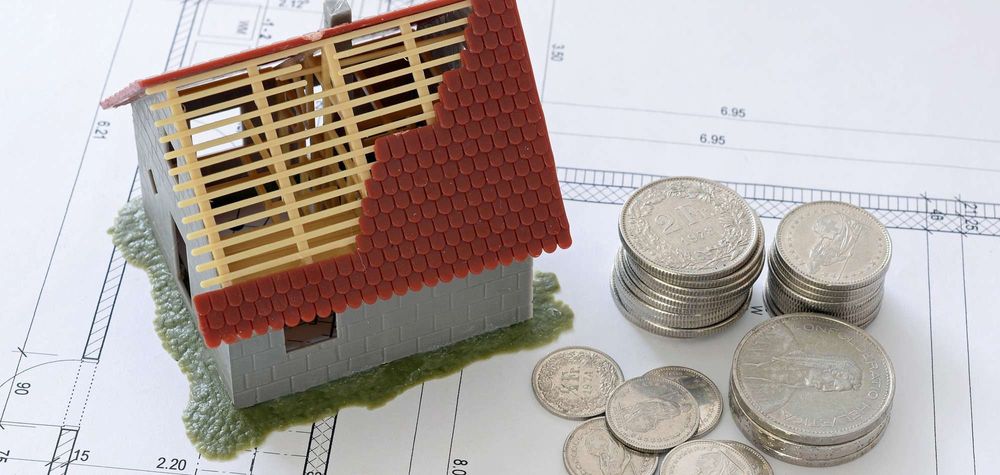 Kleines Haus und mehrere Münzen auf einer Grundrisszeichnung