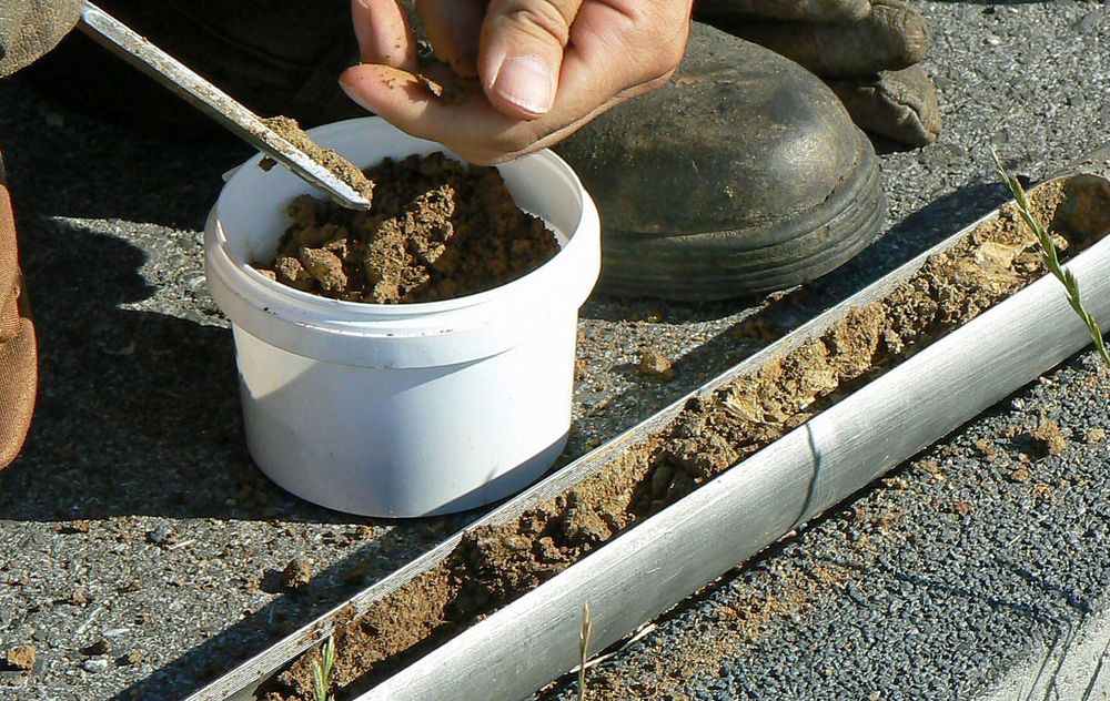 Metallrohr mit Erde drin neben einem mit Erde gefüllten Eimer