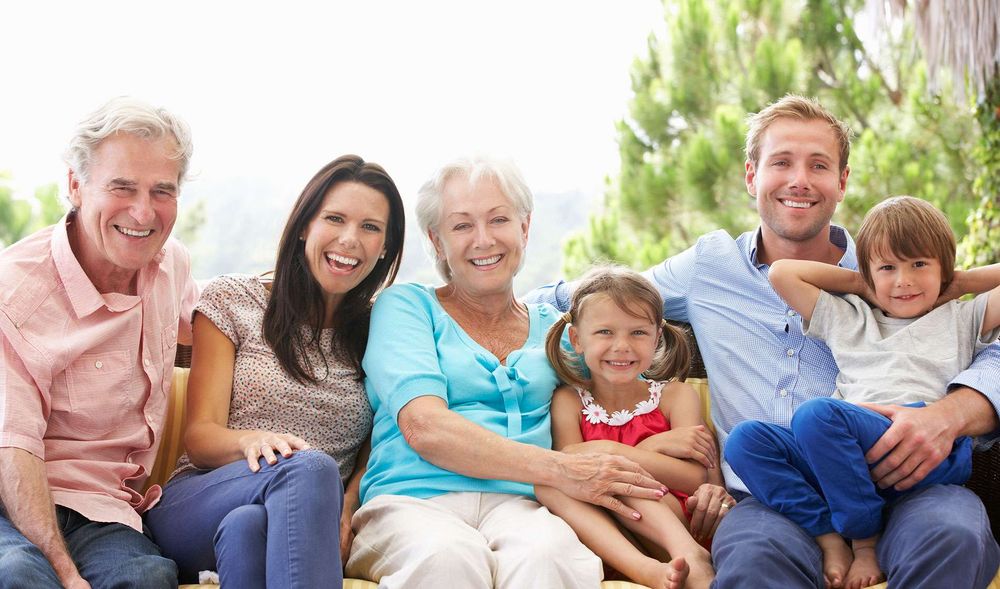 Die ganze Familie sitzt auch einem Sofa mit Garten im Hintergrund