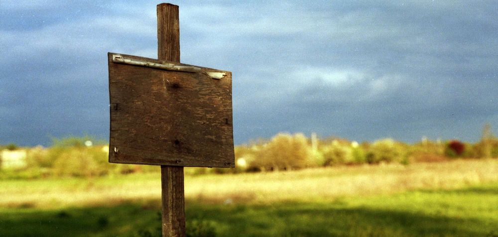 Leerstehendes Baugrundstück mit altem Holzschild