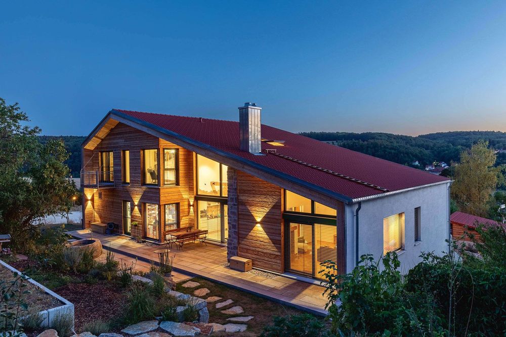 Modernes Holzhaus mit großer Holzterrasse und Abendbeleuchtung