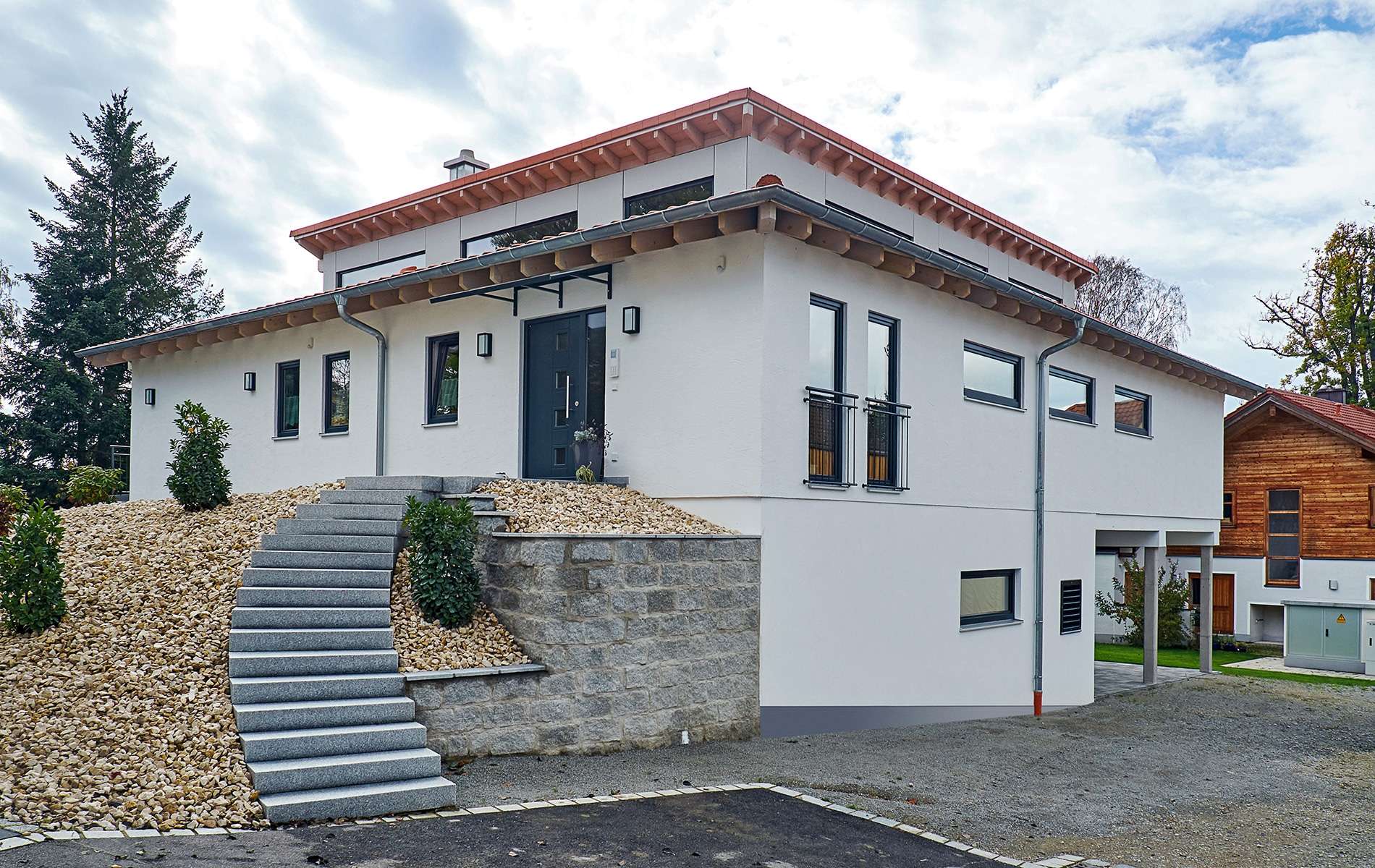 Moderner Bungalow aus Holz auf Hanggrundstück mit mineralischem Außenputz und Pultdach