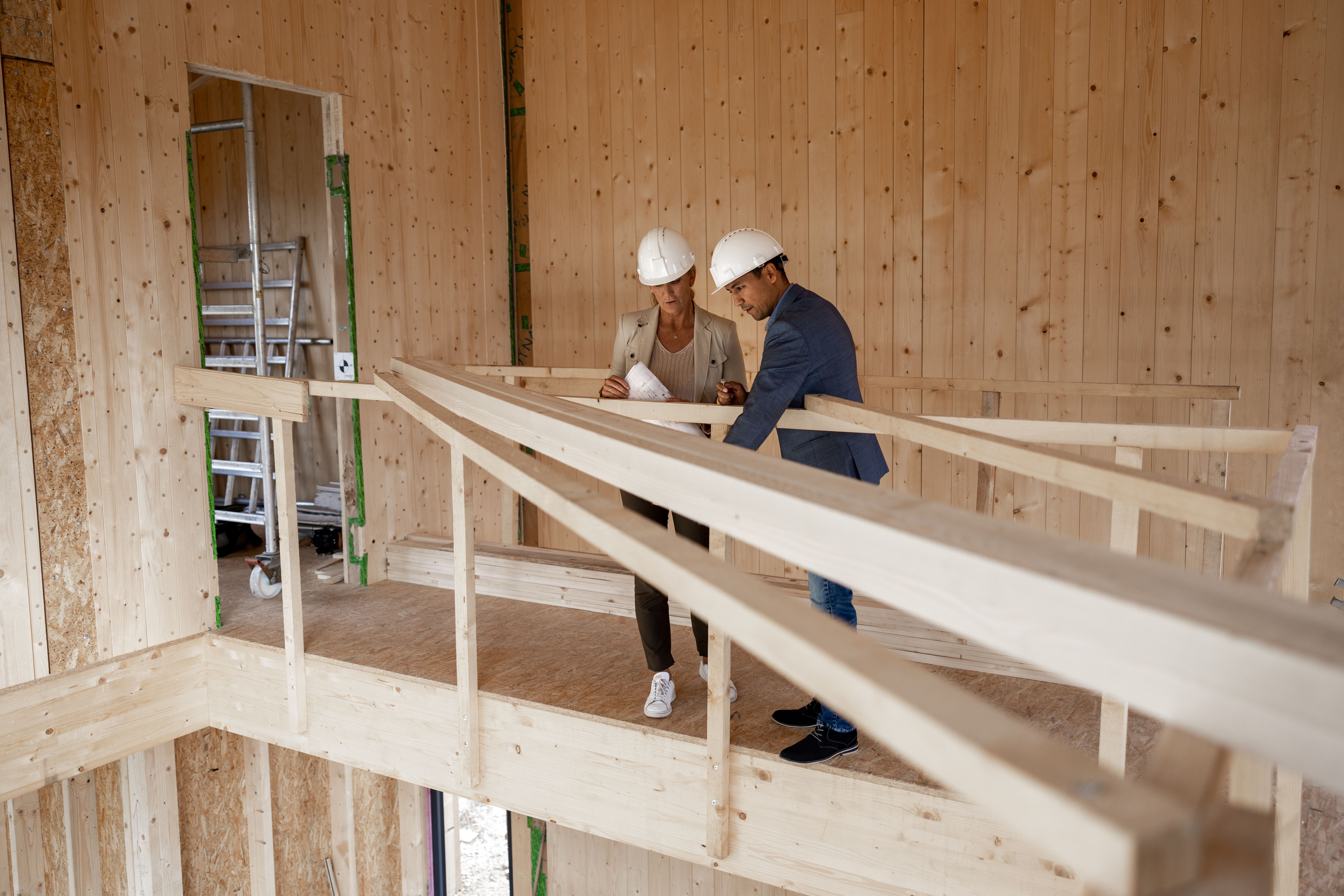 Zwei Handwerker stehen auf einer Galerie aus Bauholz