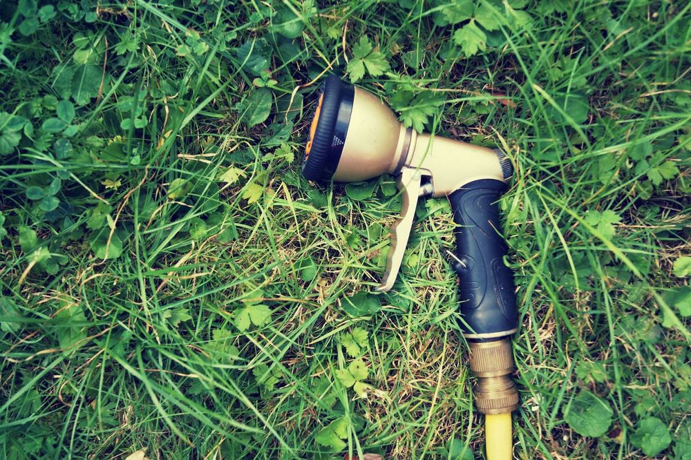 Wasserschlauch mit Düse auf grasbedecktem Boden