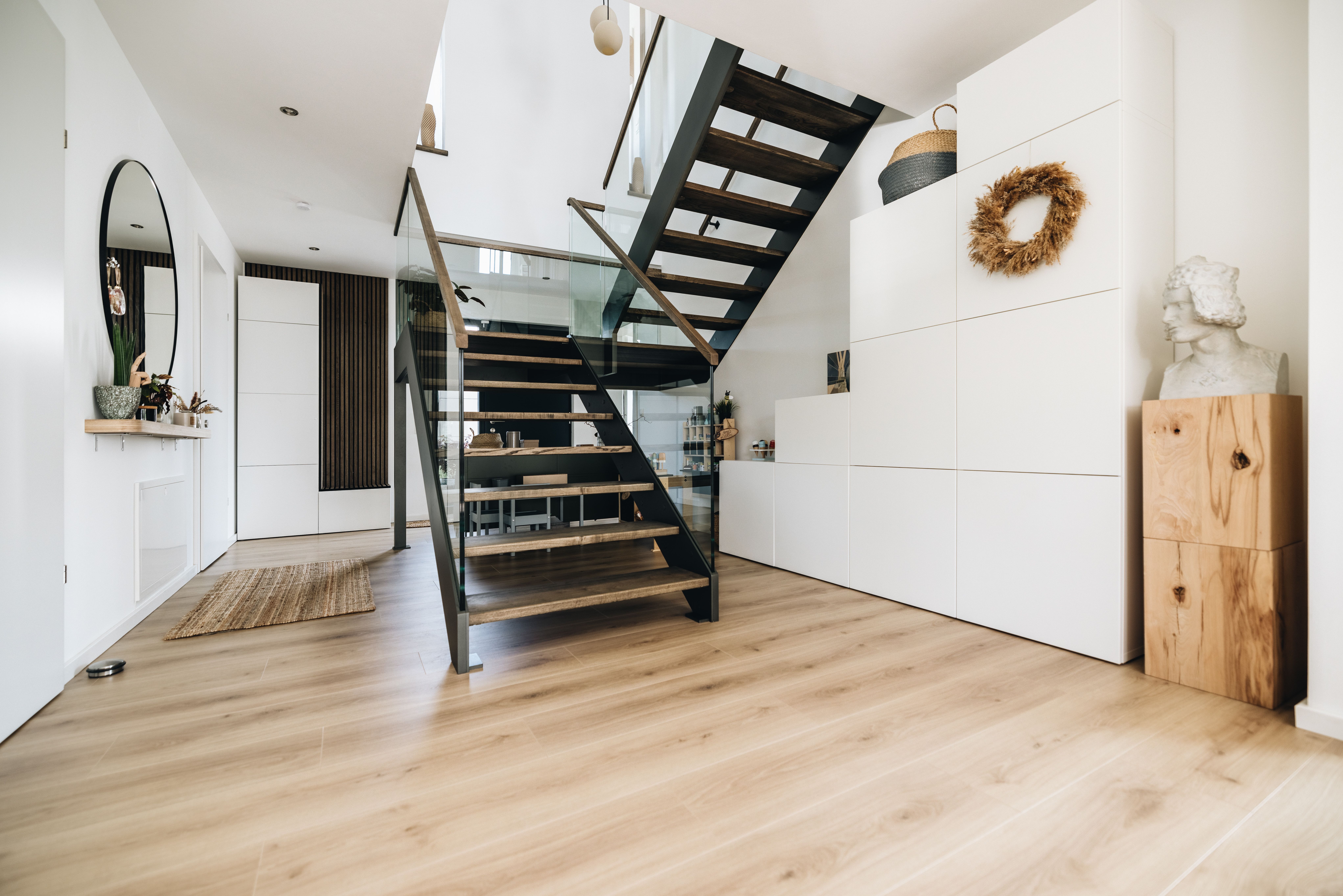 Heller Flur mit schwarzer Treppe und Holzboden