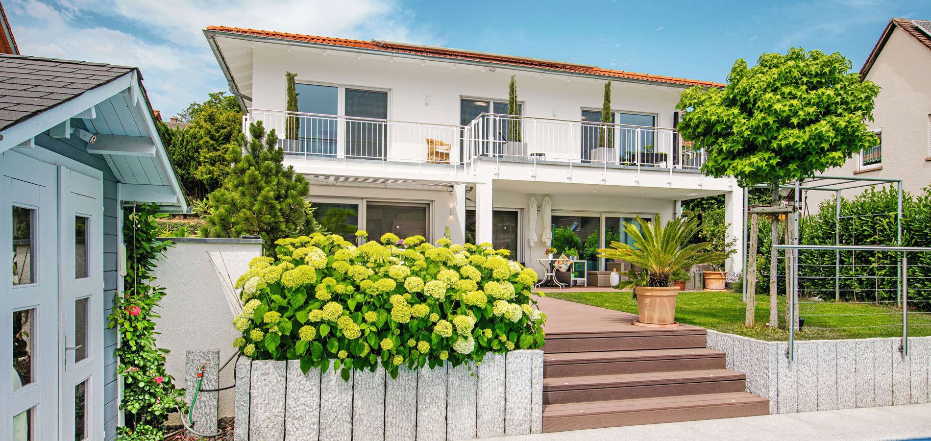Modernes Fertighaus mit Balkon, überdachter Terrasse und Garten