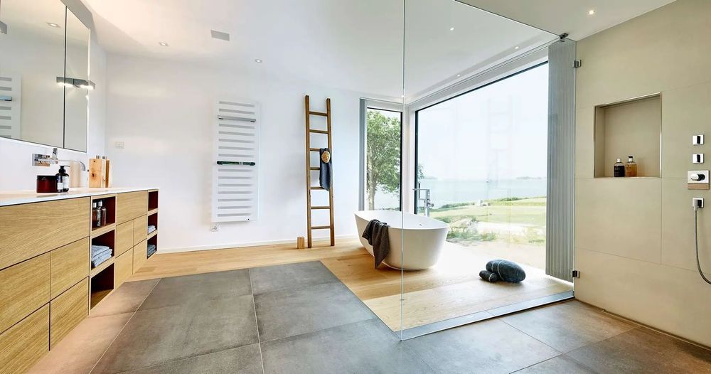 Großes Wellness Badezimmer mit freistehender Badewanne und Glasfront für den Blick ins Grüne